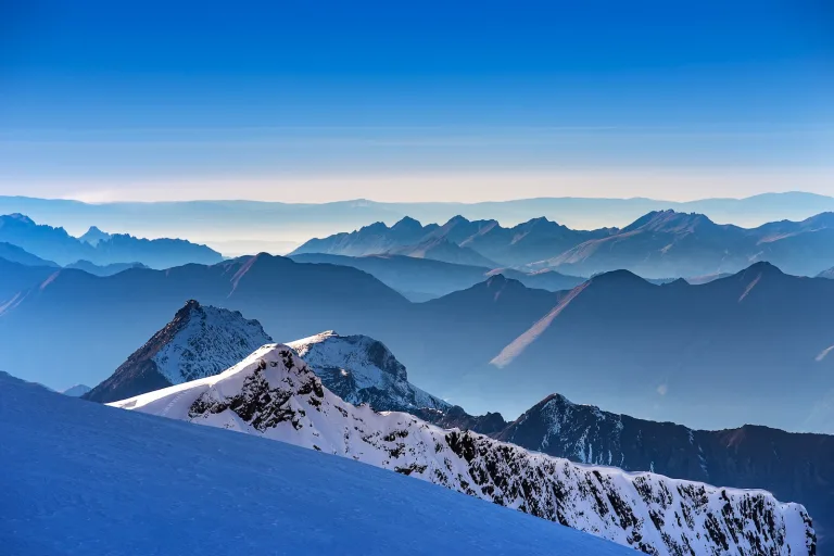 Sommets et versants enneigés devant plusieurs chaînes de montagnes.